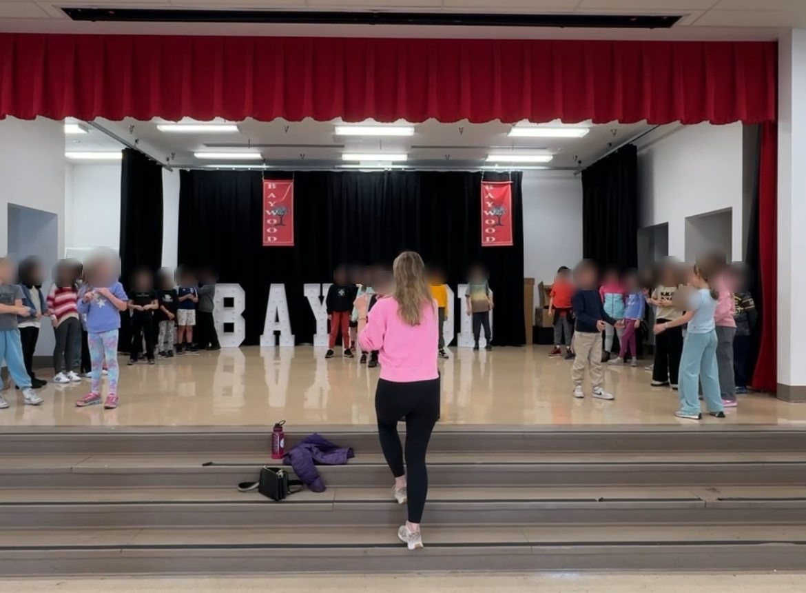 Erin Lautsch directing students in rehearsal on a school stage